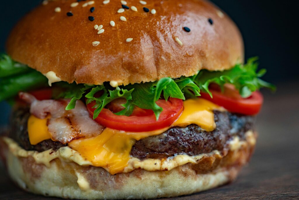 Current image: Juicy cheeseburger with bacon, lettuce, tomato, and sesame seed bun.